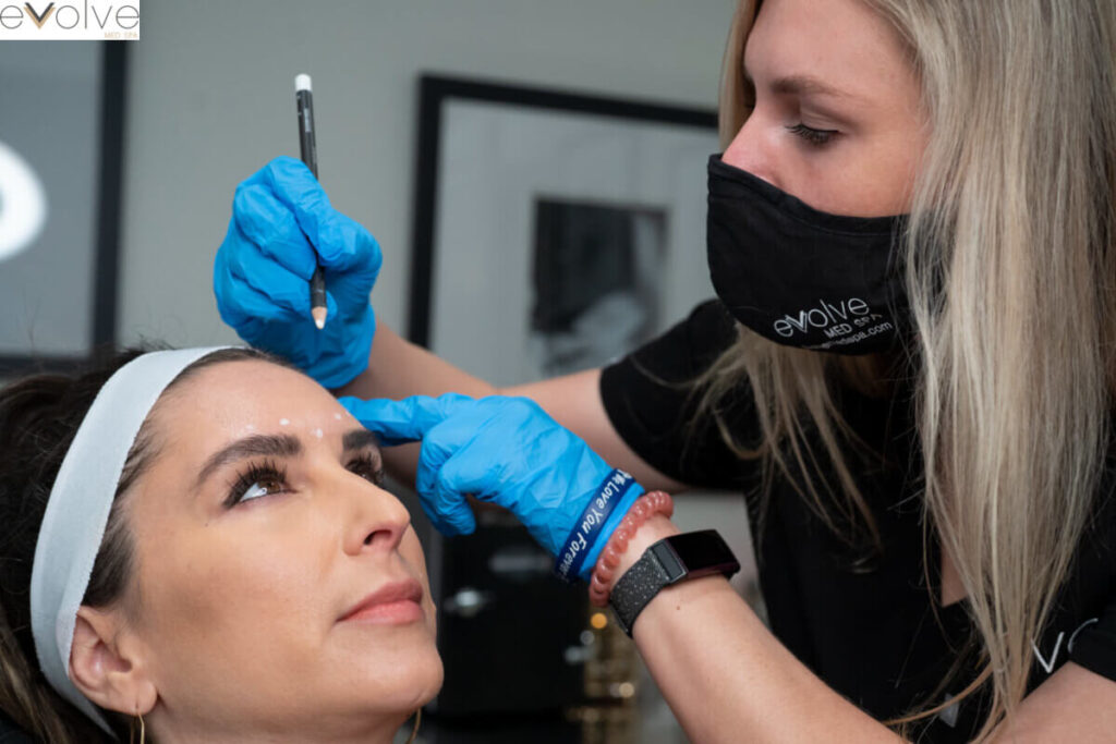 A Botox provider draws white dots on a client's forehead