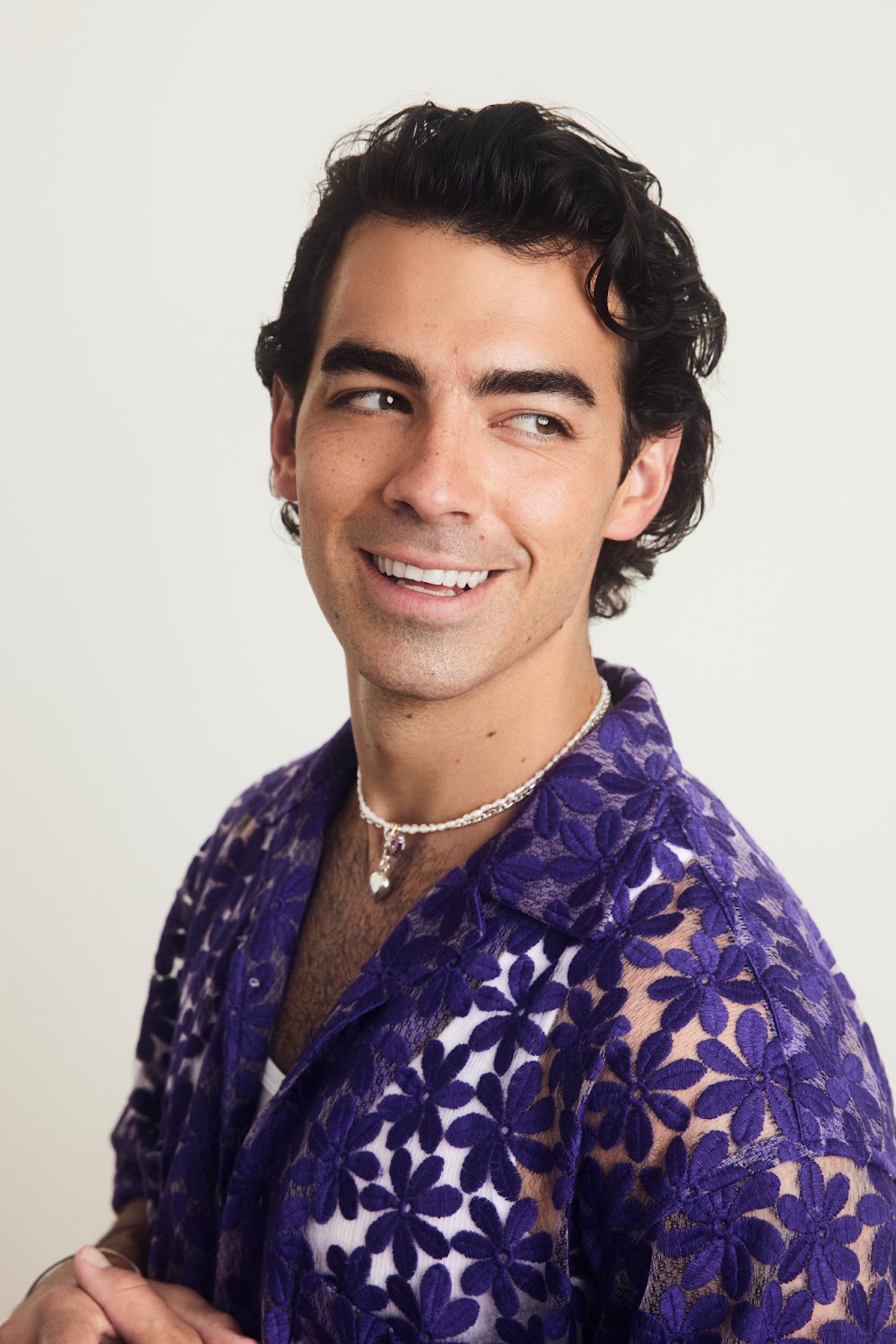 Joe Jonas wrinkle-free, smiling, and wearing a purple floral shirt