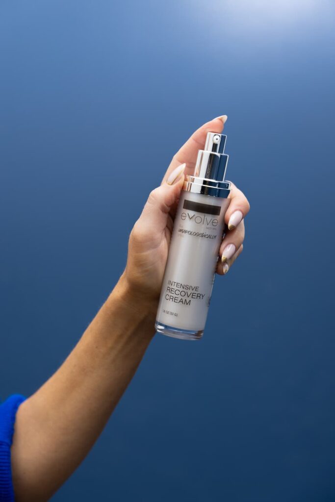 A hand holding a bottle of Evolve’s Intensive Recovery Cream.