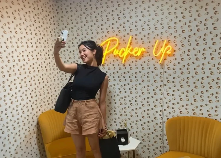 Ridgewood client in lobby in front of neon sign reading pucker up