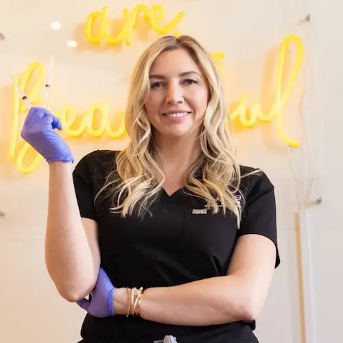 Nurse is smiling while holding a syringe in her hand.